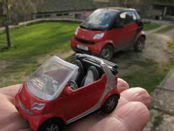 two smart cars, one a toy at about 4 inches away, the other real at 20 feet